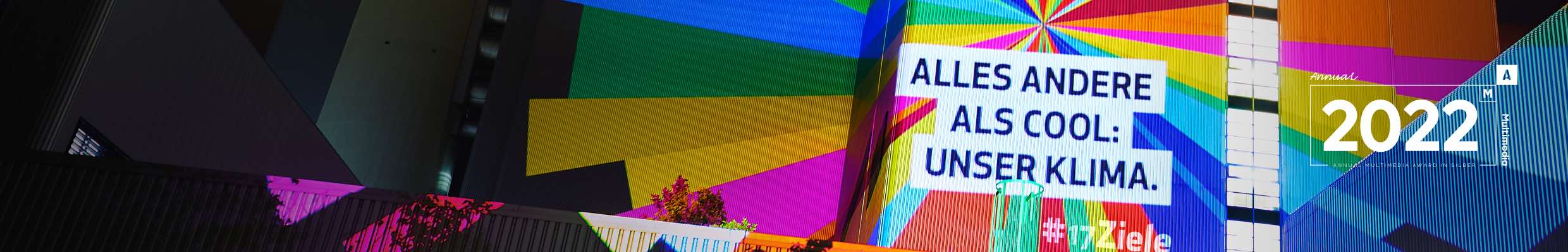 Digitaler Stunt und Social Media Kampagne mit Influencern für 17Ziele. Text, digitale Projektionen mit leuchtenden Statements zu den 17 Zielen auf symbolträchtige Gebäude und Objekte in vier Städten und vier Nächten, Verbreitung der Aktion über Social Media durch Influencer, Organisationen und eigene Kanäle, Making-of. Auszeichnung: Annual Multimedia Award Silver 2022. Bild: Lichtprojektion in Regenbogenfarben aus geometrischen Formen und Text auf eine Gebäudefassade bei Nacht.