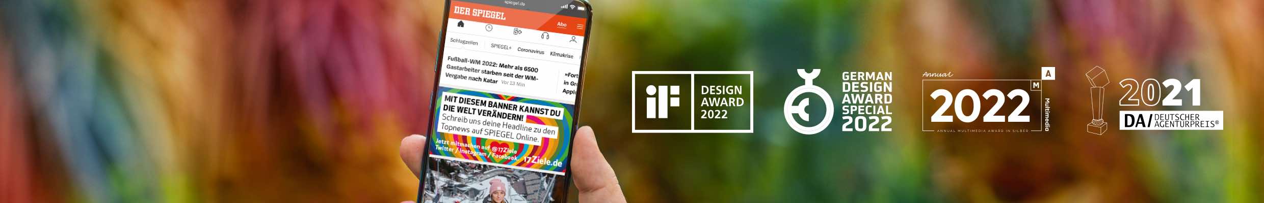 Digitaler Stunt für 17Ziele mit User-Generated Content: Verknüpfung von Social Media mit SPIEGEL online durch interaktiven 21-Stunden-Live-Banner. Leistungen: Konzeption, Aktivierung zur Teilnahme über Instagram, Facebook und Twitter, Auswahl und Ausspielung echter Kommentare in Echtzeit im Banner über dem Top-Artikel, Teilen individueller Beiträge zu den 17 Zielen für nachhaltige Entwicklung, Making-of. Auszeichnungen: iF Design Award 2022, German Design Award Special 2022, Annual Multimedia Award 2022 und Deutscher Agenturpreis 2021. Bild: Eine Hand hält ein Smartphone, auf dem Display ein bunter Werbebanner auf einer Nachrichtenseite; der Hintergrund ist unscharf und farbenfroh.