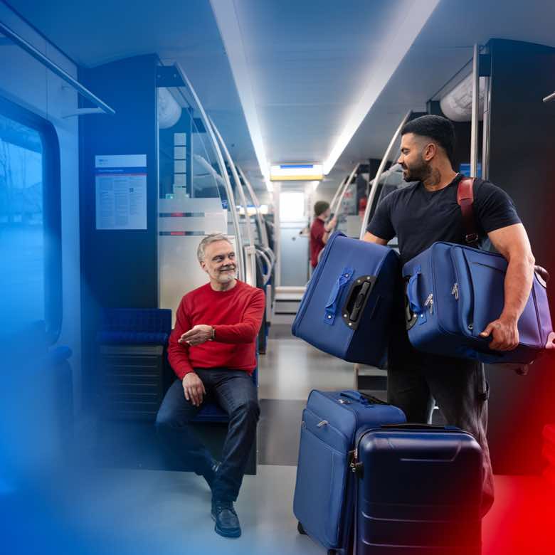 Kampagne für die S-Bahn Hannover. Konzeption, Imagekampagne in zwei Phasen, Fotoshooting, Postingdesigns, Storys und Reels für Social Media, Print- und OOH-Motive, digitale Anzeigen. Bild: Dynamische Innenansicht eines S-Bahn-Waggons mit blauen Sitzen; ein Mann bepackt mit Koffern steht vor einem sitzenden Fahrgast, der vor sich zur Seite weist. Beide lächeln. Text: WIR GEBEN ALLES.