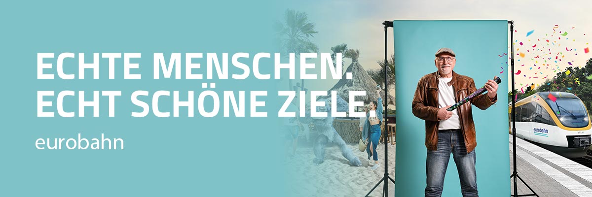 Kampagne für die eurobahn. Konzeption und Umsetzung einer integrierten Imagekampagne, Kampagnenslogan, Fotoshooting mit Interviews, OOH-Motive, Printanzeigen, digitale Kampagne für Social Media und Suchmaschinen, GIFs. Bild: Ein älterer Herr in Jeans und Lederjacke steht mit Konfettikanone vor einer türkisfarbenen Fotoleinwand am Bahnsteig; im Hintergrund links eine Strandszene, rechts ein Regionalzug. Text: ECHTE MENSCHEN. ECHT SCHÖNE ZIELE.