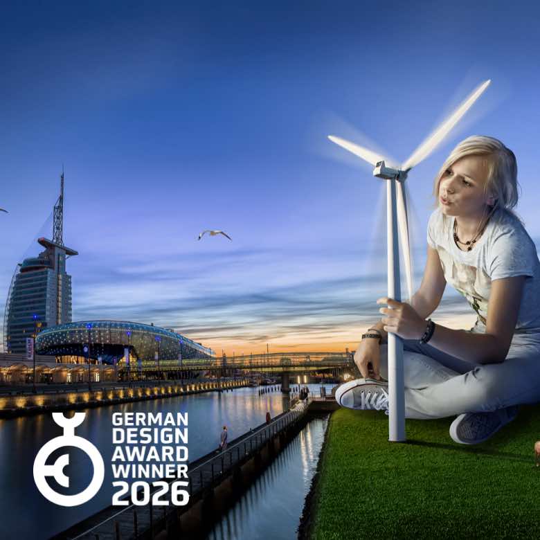 Kampagne für das Klimahaus Bremerhaven umgesetzt in DOOH, Anzeigen, Social Media, Kampagnenplanung und Radiospots. Bild: Eine junge Frau hält ein Modell eines Windrads vor der nächtlichen Skyline von Bremerhaven mit dem Klimahaus-Gebäude und dem beleuchteten Hafenbecken im Hintergrund. Text: WIR HABEN ES IN DER HAND. Ausgezeichnet mit dem German Design Award 2026.