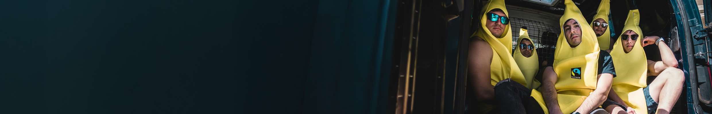 Social-Media-Kampagne für Fairtrade Deutschland. Konzeption, Fotoshooting mit Mitarbeitenden, Postproduktion, Schnitt und Gestaltung von Reels und Captions für Social Media, Kampagnenplanung, Kampagnenauswertung, Community Management. Bild: Fünf Personen sitzen gedrängt im Laderaum eines Transporters; alle tragen leuchtend gelbe Bananenkostüme und Sonnenbrillen und blicken cool in die Kamera. Text: VOLL IM FAIRTRADE-FIEBER.